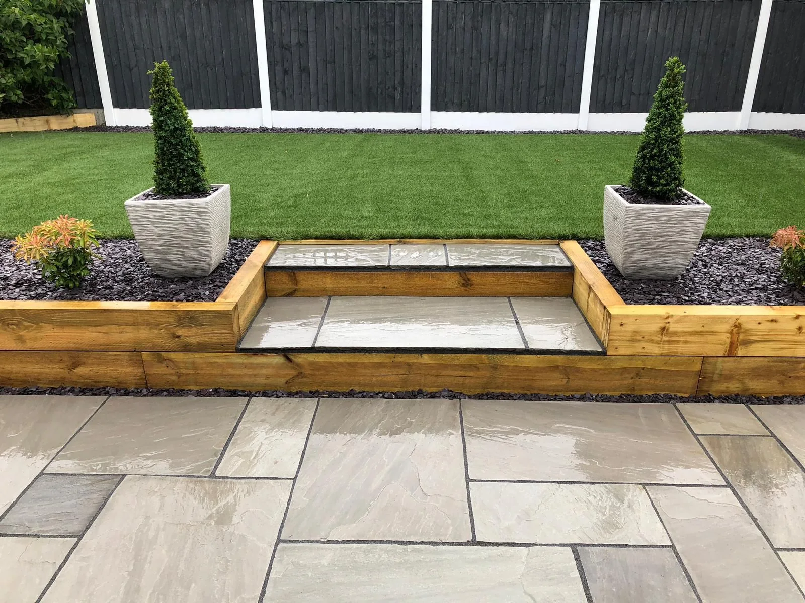 Completed stone patio with steps, planting and neatly finished lawn edges